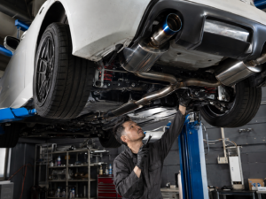 Mechanic inspecting suspension brakes and exhaust on a modified imported performance car